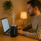 omme concentré devant son ordinateur portable, accompagné d’un diffuseur noir à éclairage LED multicolore diffusant de la vapeur sur un bureau en bois, dans une ambiance douce et tamisée